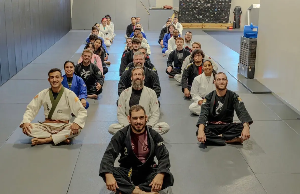 Finesse students and coaches seated together on the academy mats