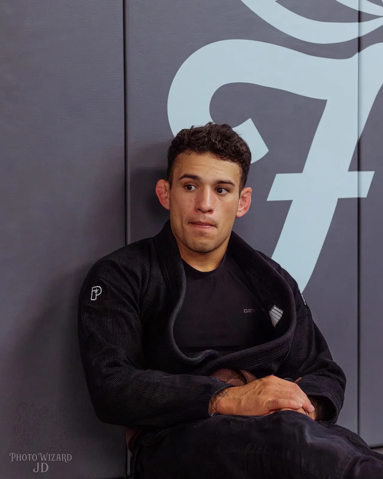 A student in a black gi beside the Finesse wall logo