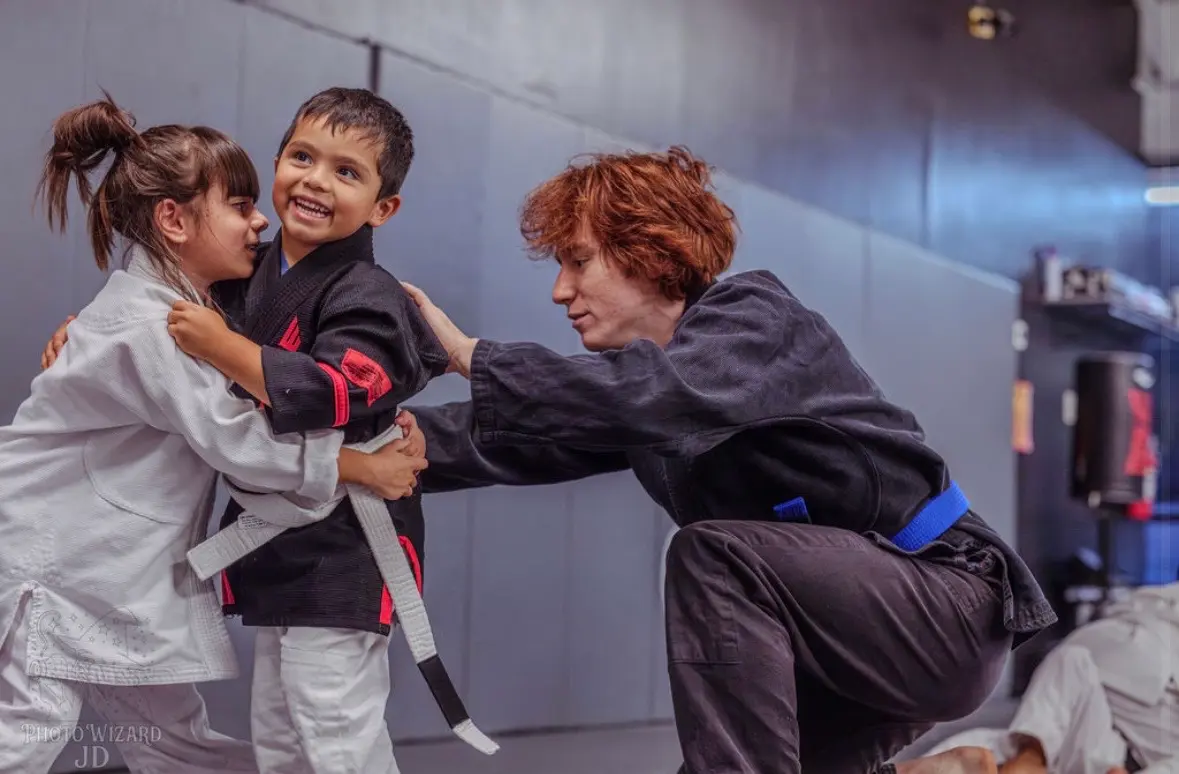 A coach guiding young students through a grappling drill