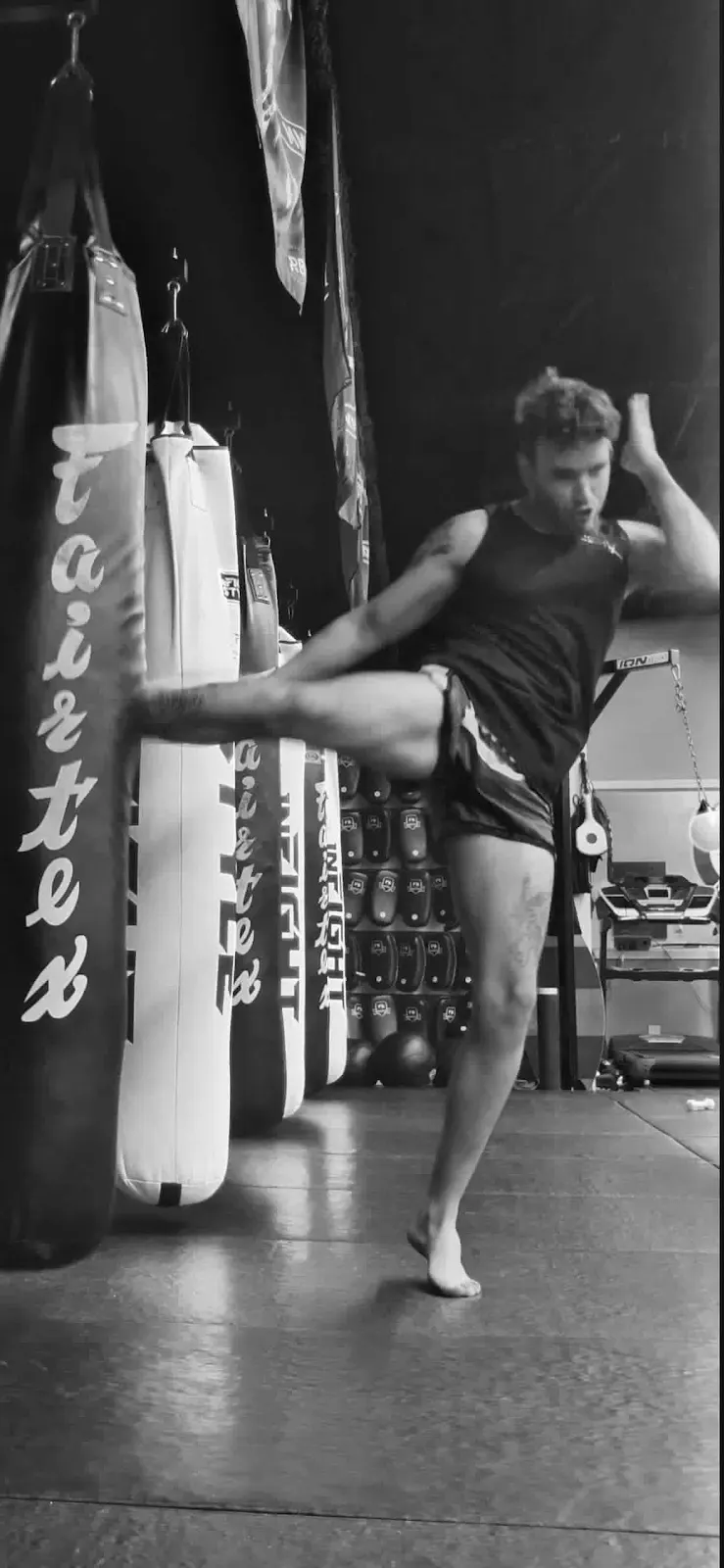 An athlete practicing a kick on a heavy bag